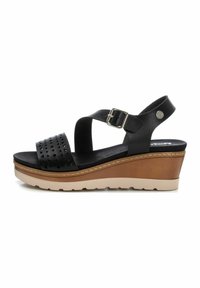 Sandalias de cuña negras con una correa de cuero perforado, hebilla ajustable y una suela de cuña de color marrón claro con un acabado texturizado.