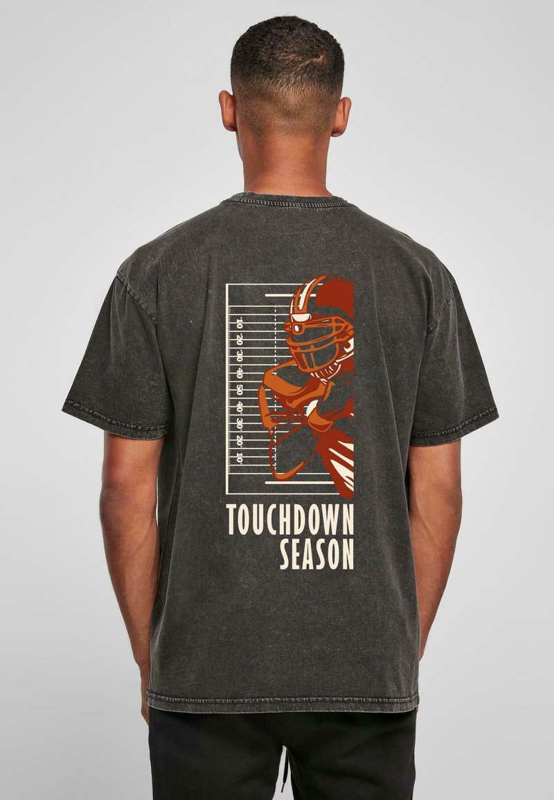 Čierne bavlnené tričko s grafikou futbalistu a textom "TOUCHDOWN SEASON" v béžovej farbe na zadnej strane, s opotrebovaným vzhľadom.