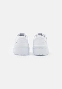 Vita lädersneakers med en slät yta, rund tå, vadderad krage och strukturerad gummisula. Har minimal detaljering och sömnad.