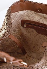 Flettet halmearmbånd med brune læderdetaljer, med beige foer med gentaget logo, indvendig lynlåslomme og skulderremme.