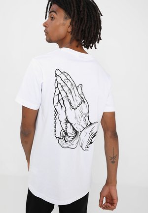White t-shirt featuring a black graphic of clasped hands with a rosary. Short sleeves and a crew neckline. Smooth cotton texture.