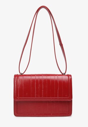 Crvena torba preko tijela od umjetne kože s teksturom nalik krokodilskoj koži. Ima preklopni zatvarač i jedan podesivi remen.