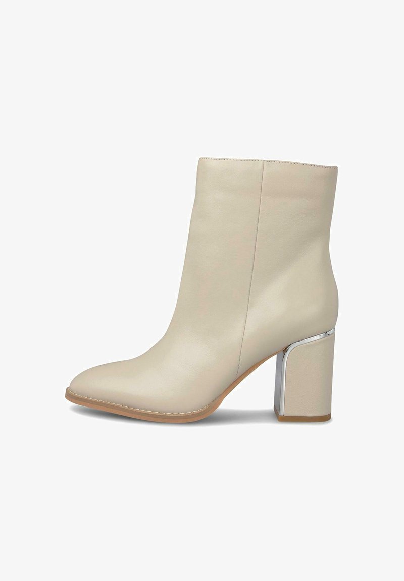 Botín beige hasta el tobillo con punta afilada, textura de cuero suave y un tacón cuadrado con acentos plateados. Diseño minimalista y acabado sin costuras.