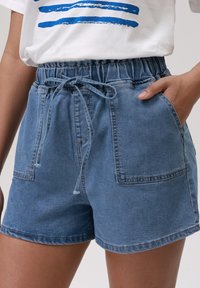Τζιν σορτσάκια σε ανοιχτό μπλε χρώμα με ελαστική μέση, κορδόνι και δύο εμπρός τσέπες. Διαθέτουν άνετη εφαρμογή και απαλό υλικό.