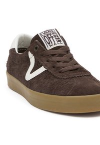 Baskets Vans en daim marron avec logo blanc, lacets marron et semelle en gomme, présentées légèrement inclinées sur fond blanc.