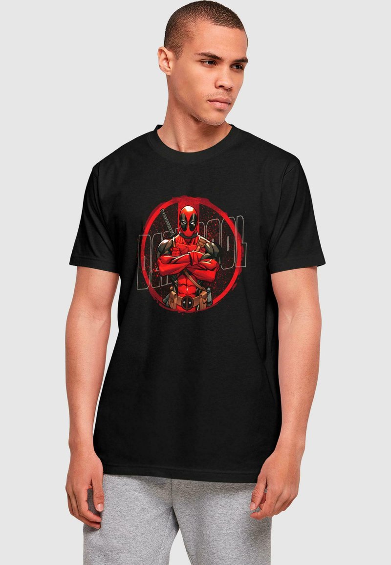 Svart bomull t-skjorte med et fargerikt Deadpool-grafikk i rødt og svart, sentrert i et sirkulært design. Korte ermer, rund hals.