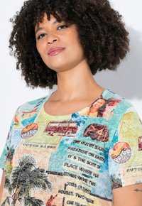 T-shirt met korte mouwen met een kleurrijk, gemusterd ontwerp met afbeeldingen en tekst over de Outer Banks, gemaakt van een lichte, gestructureerde stof.