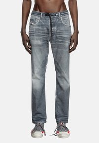 Jean en denim gris délavé avec une coupe décontractée, comprenant une taille à cordon, cinq poches et des détails de couture contrastés.