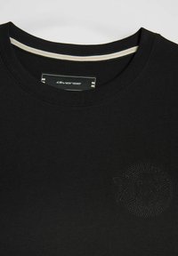 Czarna koszulka z krótkim rękawem i okrągłym dekoltem. Posiada teksturowane logo w dopasowanym kolorze. Cienki, kontrastowy pasek wewnątrz kołnierza.