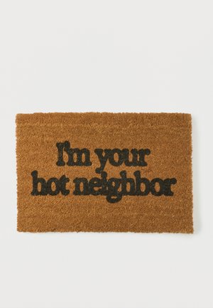 Brown coir doormat with black text reading, "I'm your hot neighbor" centered on a plain white background.