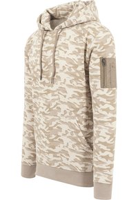 Kamuflasje hettegenser i beige toner, med snøring i hetten, frontlomme og glidelåslomme på ermet. Myk stoff med ribbestrikkede mansjetter.