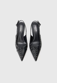 Melni ādas slingbeka apavi ar smailiem purngaliem, mežģīņu detaļām un maziem metāla kniedēm gar malu. Gluda tekstūra, moderns dizains.