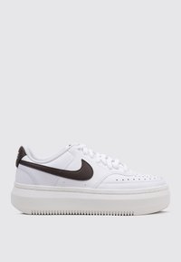 Zapatilla de cuero blanca con punta redonda, swoosh de Nike marrón, detalles perforados y una gruesa suela de goma blanca.