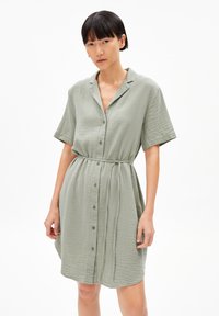 Vestito a maniche corte, con bottoni, realizzato in morbido tessuto verde chiaro a trama. Presenta una vestibilità rilassata e una vita legata per sagomare.