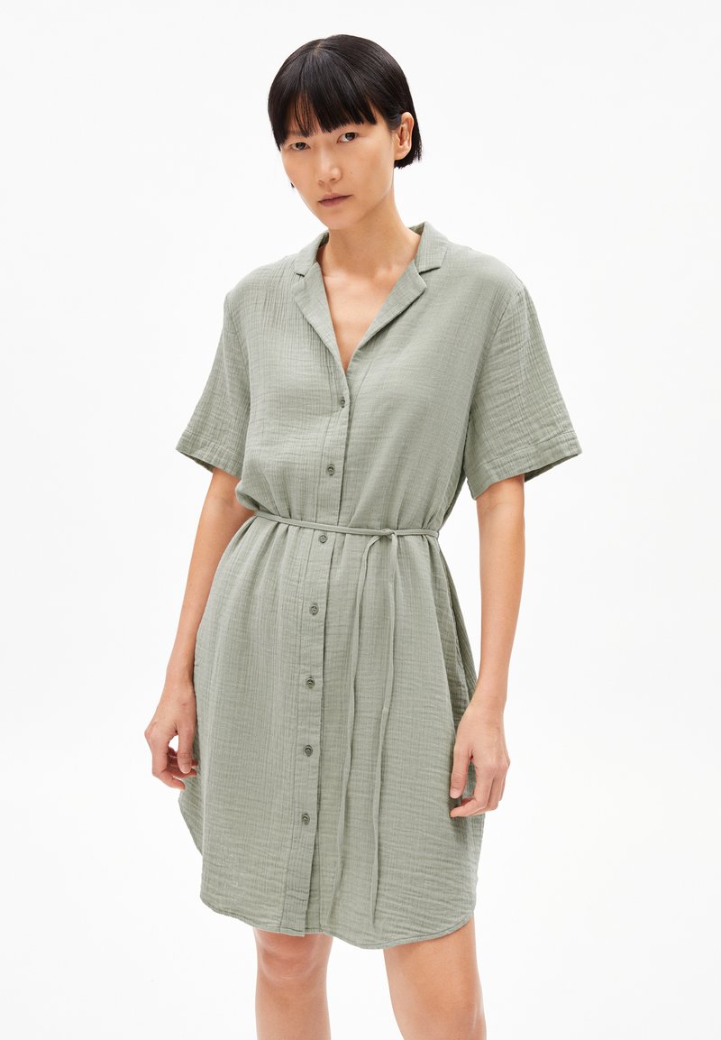 Vestito a maniche corte, con bottoni, realizzato in morbido tessuto verde chiaro a trama. Presenta una vestibilità rilassata e una vita legata per sagomare.