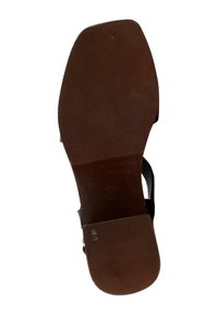 Suola in gomma marrone di un sandalo con superficie testurizzata, che mostra segni di usura. Le cinghie non sono visibili, evidenziando il design e la forma della suola.