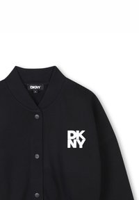 Giacca bomber nera DKNY con colletto a coste, chiusura a bottoni e stampa del logo bianco sul lato sinistro del petto. Tessuto morbido.
