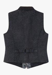 Jeansväst i mörkblått med texturerad yta, med en spänne bak och paisleymönstrad fodring synlig vid fållen.