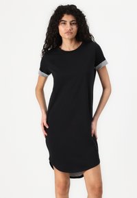 Robe t-shirt noire à manches courtes ; poignets gris retroussés. Tissu doux et lisse. Coupe droite avec un ourlet légèrement incurvé.