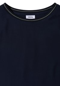 T-shirt bleu marine avec un col rond présentant deux fines rayures gris clair et une étiquette blanche à l'intérieur du col avec le texte "CECIL".