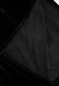 Czarna tkanina aksamitna, miękka w dotyku, z gładką podszewką wewnętrzną. Krawędzie są przeszyte dla trwałości, co tworzy estetyczne wykończenie.