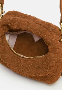 Borsa a tracolla in suede marrone con texture intrecciata, zip dorata e fodera chiara all'interno. La forma è arrotondata con una singola tracolla.