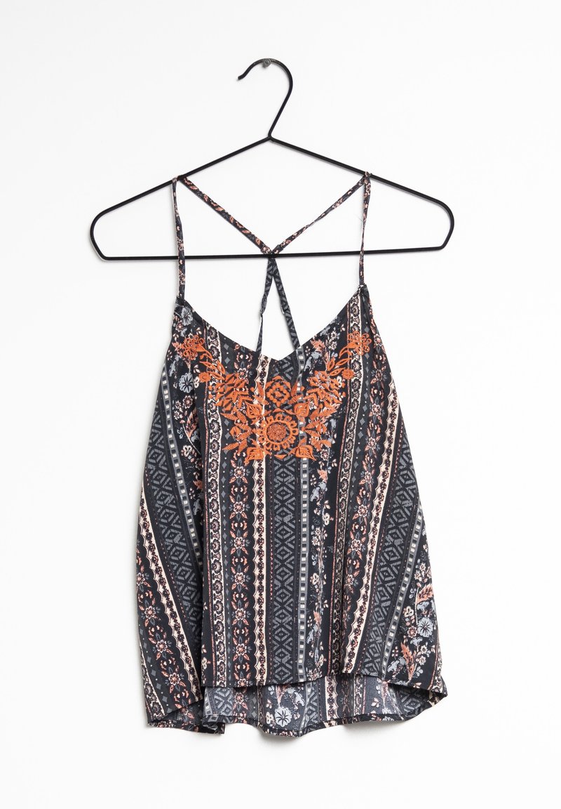 Haut sans manches à motif floral noir et orange avec fines bretelles croisées, accroché à un cintre en fil de fer noir sur fond blanc.