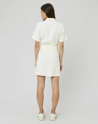Robe à manches courtes et col en jaune pâle, présentant une taille ajustée et une jupe évasée. Tissu texturé, avec un design épuré et minimal, vue arrière.