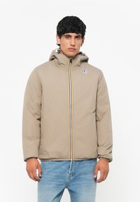 Beige pufferjakke med hætte, frontlynlås og farverige stribede detaljer. Har et logo-lap på brystet og elastiske manchetter.
