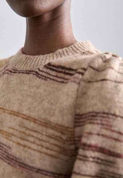 Beige ullgenser med rund hals, med tynne horisontale striper i brun og maroon. Teksturen ser myk og strikket ut.
