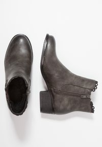 Szare botki za kostkę o gładkim wykończeniu, z suwakiem po boku i falbaniastym wykończeniem na górze. Słupkowy obcas, teksturowana podeszwa i zaokrąglony czubek.