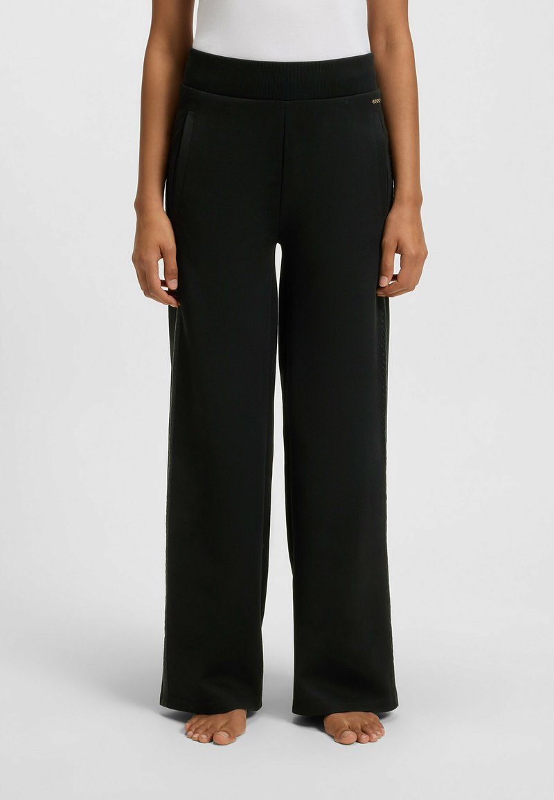 Relaxed fit, zwarte sweatpants met een wijde pijp, geribde tailleband, zijzakken en een gladde textuur. Geen zichtbare logo's of patronen.