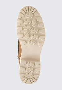 Botte en cuir marron avec une semelle en caoutchouc beige texturé présentant des motifs de profil profond, idéale pour l'adhérence et la traction. Taille 40 indiquée sur la semelle.