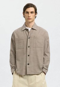 Langærmet skjorte med ternet mønster i beige og brune nuancer, med krave, to brystlommer og sorte knapper. Materiale i bomuldsblanding.