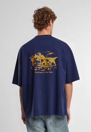 T-shirt surdimensionné bleu marine avec un graphisme doré d'animaux au dos, en coton, avec un col rond et des manches courtes.