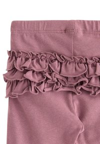 Roze legging met een gerimpelde laag aan de taille, gemaakt van zachte, rekbare stof. Naaddetail zichtbaar boven de rimpels.