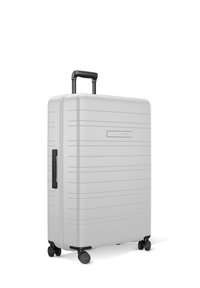 Silver hard-shell suitcase with horizontal ridges, a retractable black handle, and four swivel wheels for easy mobility.