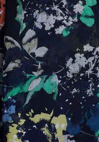 Blommönstrad tyg med en mörk marinblå bakgrund och livfulla gröna blad samt vita blommor, vilket skapar en texturerad, lager-på-lager design.