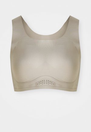Sømløs beige sports-bh med brede stropper og små ventilasjonsåpninger under brystbåndet for pusteevne.