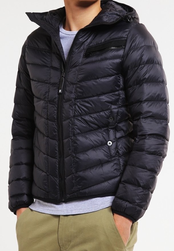 Svart pufferjacka med huva, med kviltat mönster, dragkedjefickor och en slät, glänsande textur. Stängning med dragkedja fram.