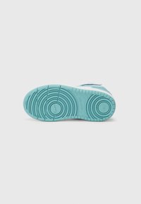 Semelle de sneakers en caoutchouc bleu clair avec un motif de semelle circulaire et une texture antidérapante. Semelle intermédiaire blanche. Présente un logo sur le côté.
