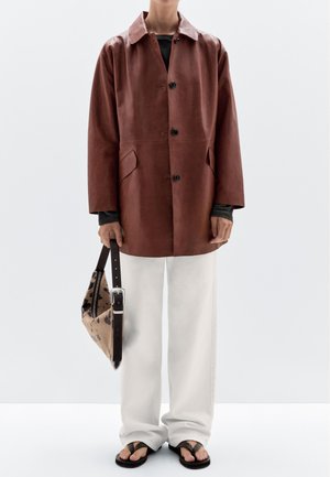 Bruine leren jas met een kraag, voorzien van knopen en zijzakken. Gecombineerd met witte wijde broek, zwarte slippers en een gestreepte tas.