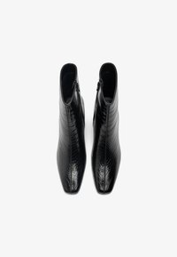 Botine negre la glezna, cu un design elegant și un model texturat de crocodil. Dispune de vârf ascuțit și fermoar lateral pentru a facilita purtarea.