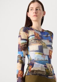 Maglia a maniche lunghe con stampa di cartoline colorate su un tessuto semi-trasparente. Collo rotondo, forma aderente e immagini varie su tutta la superficie.