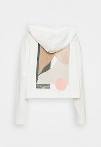 Vit beskuren hoodie med långa ärmar och abstrakt geometrisk design i beige, rosa och mörkgrön på baksidan.