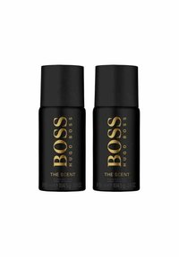 Mustasilmukkeet deodorantista mustilla sylinterimäisillä muodoilla, joissa on kultainen teksti "BOSS HUGO BOSS THE SCENT". Jokaisen pullon tilavuus on 150 ml.