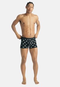 Czarne kąpielówki z powtarzającym się białym wzorem logo, wykonane z elastycznego materiału, z dopasowanym krojem i elastycznym pasem.