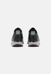 Black leather sneakers with a textured finish, grey rubber sole, and mint green heel accent, featuring a sleek, modern design.