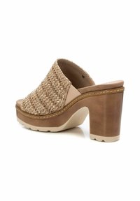 Sandalo scivoloso beige intrecciato con una fascia larga, soletta imbottita e tacco spesso marrone. La superficie testurizzata e i dettagli delle cuciture sono visibili.