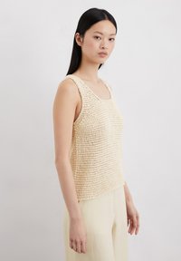 Beige gebreide tanktop met een ronde hals en brede banden, met een gestructureerd, open geweven ontwerp dat ademend vermogen toevoegt.